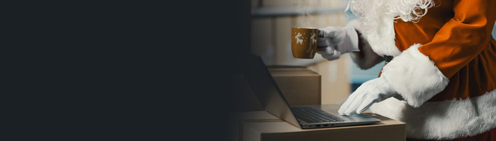 Weihnachtsmann mit Paketen arbeitet am Laptop